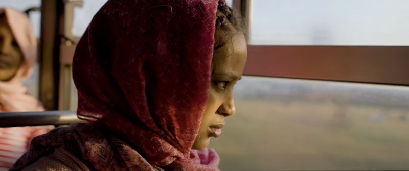 Close-up of a young woman in a red headscarf, a frame from the Adam Smith series shot in Ethiopia