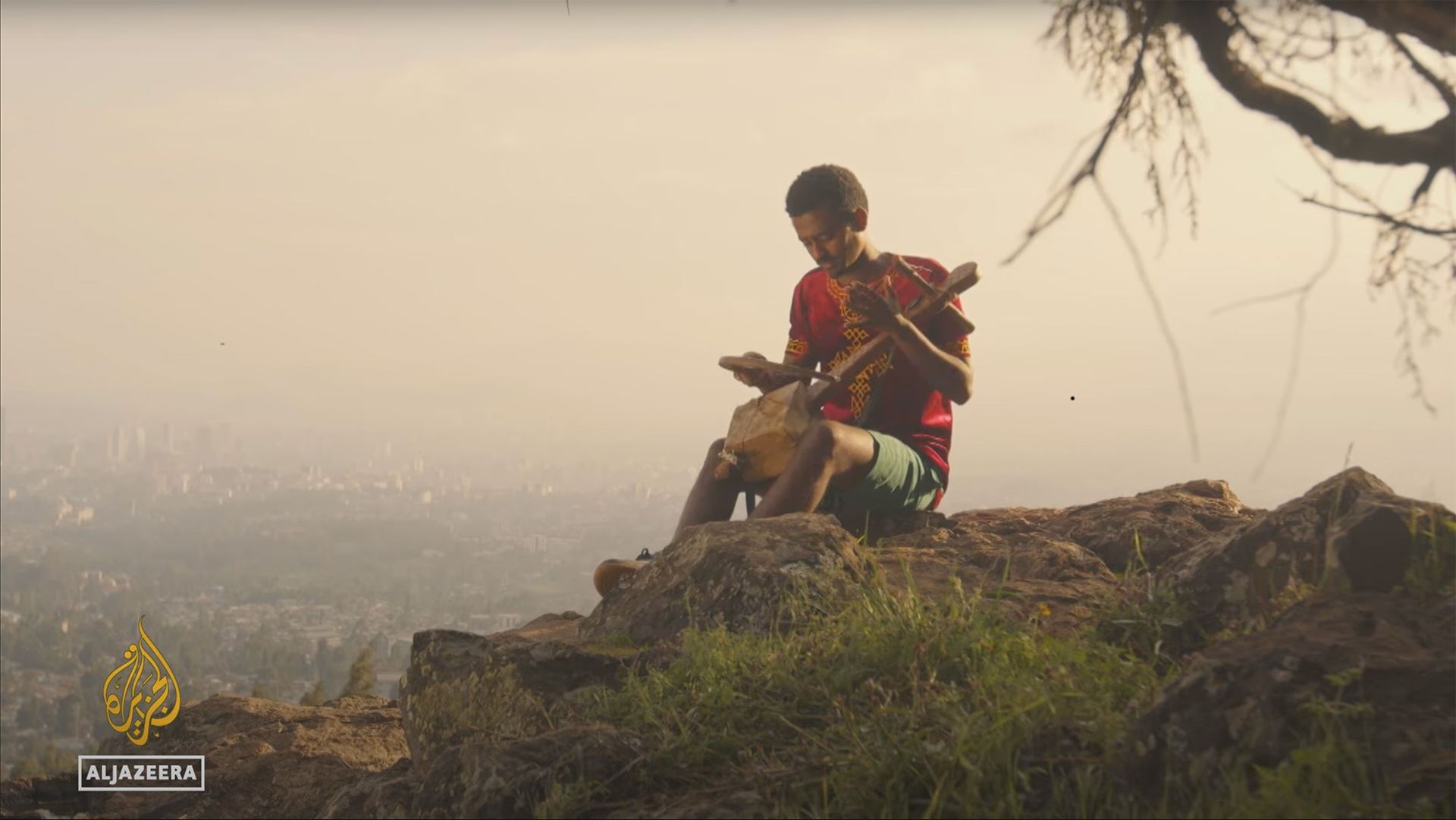 A young Ethiopian azmari musician plays the masenqo on a highland cliff edge above the Rift Valley at sunrise