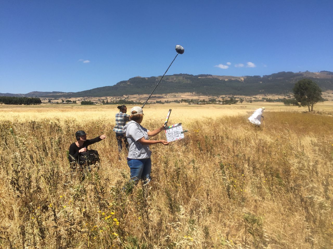 Camera operator and boom operator filming in a golden barley field in the Ethiopian highlands