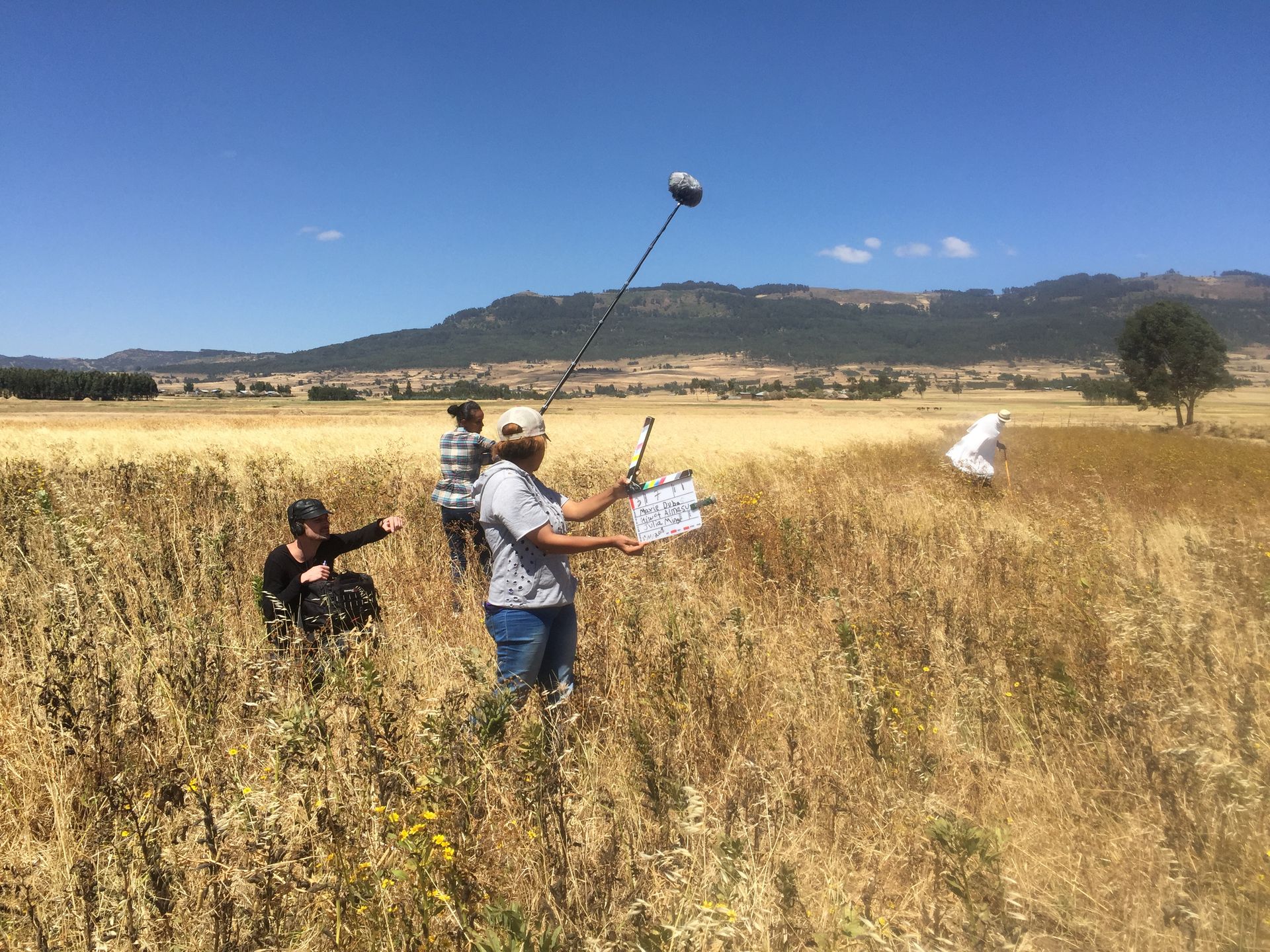 Camera operator and boom operator filming in a golden barley field in the Ethiopian highlands