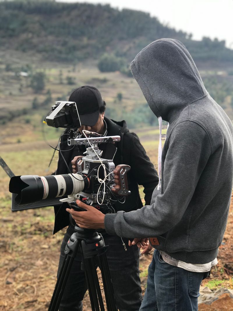 Ethiopian camera operator carrying a gimbal-mounted cinema camera on location in the highlands